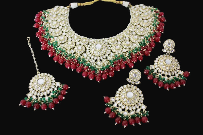 Ornate necklace set with red and green stones on a black background
