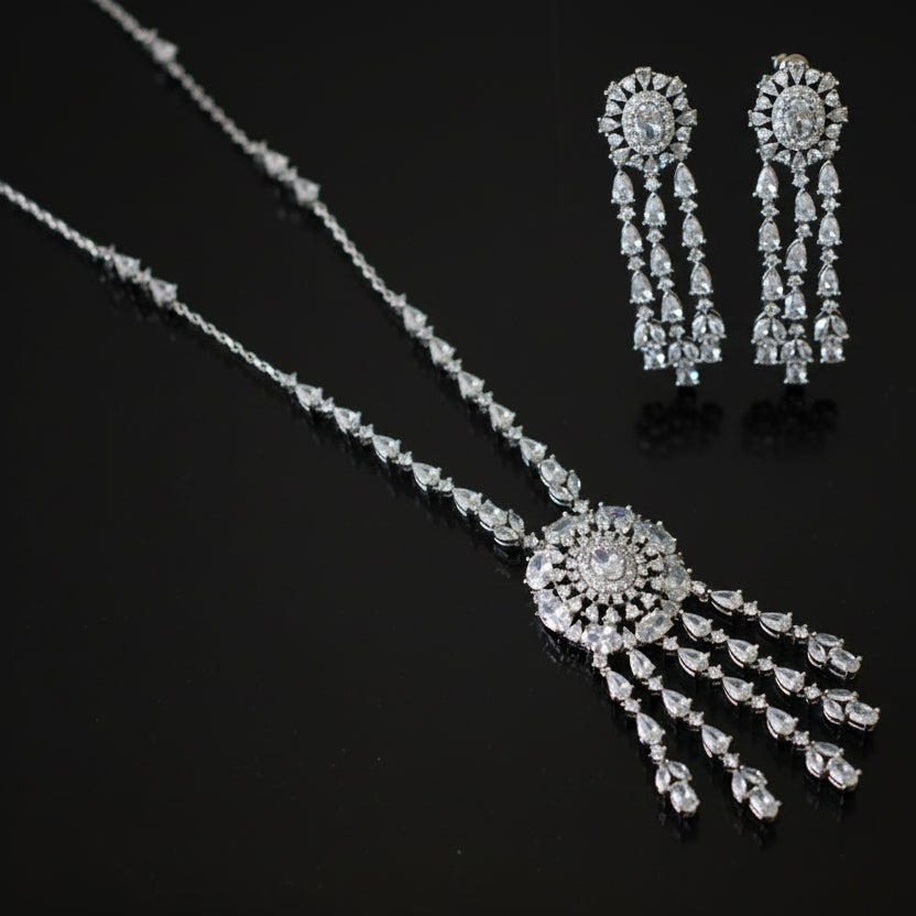 Silver necklace and earrings set on a black background