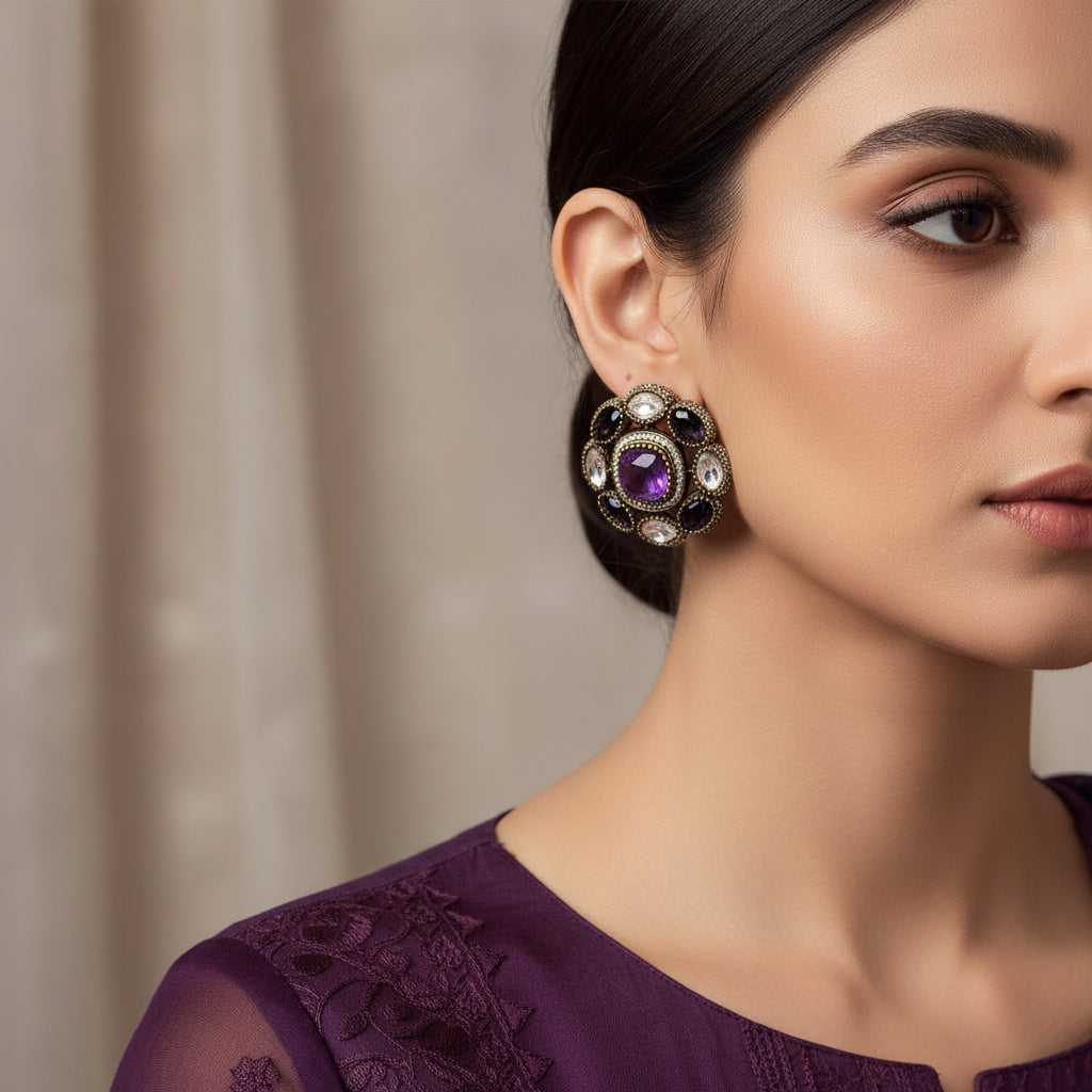 Pair of earrings with purple gemstones and decorative stones on a light gray background.